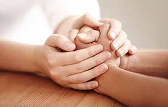 one pair of hands holds another pair of hands in a comforting gesture