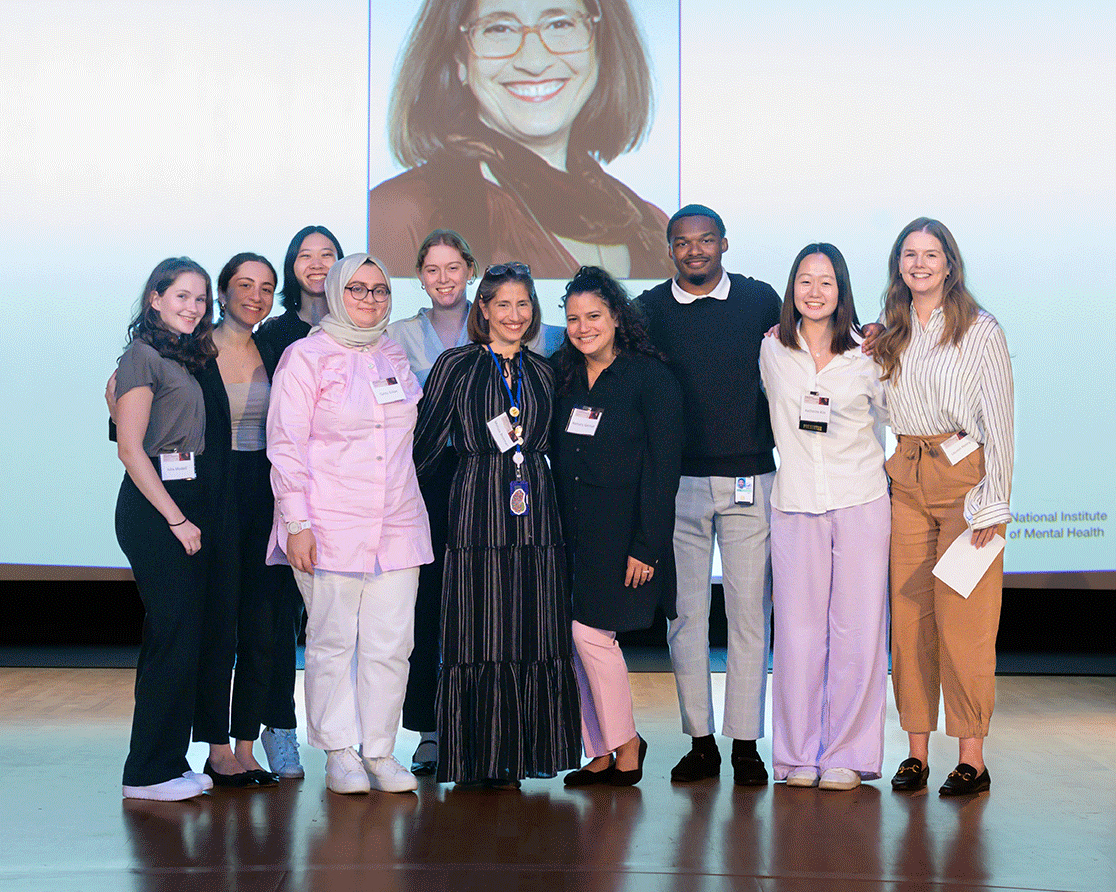 Melissa Brotman on stage surrounded by mentees. 