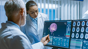 Two Medical Scientists in the Brain Research Laboratory Discussing Progress on the Neurophysiology Project Fighting Tumors. Neuroscientists Use Personal Computer with MRI, CT Scans Show Brain